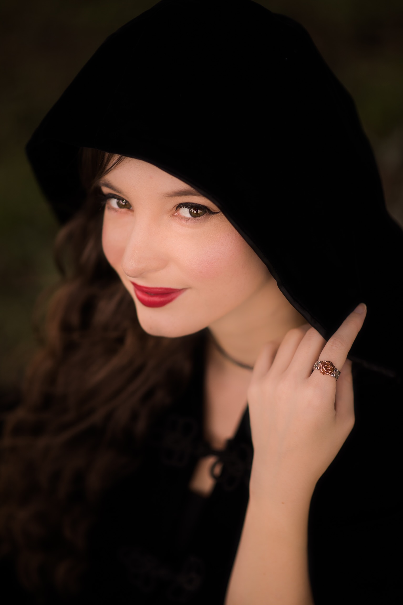 Author photo of Hannah Carter; woman with black hooded cape looks at camera. 