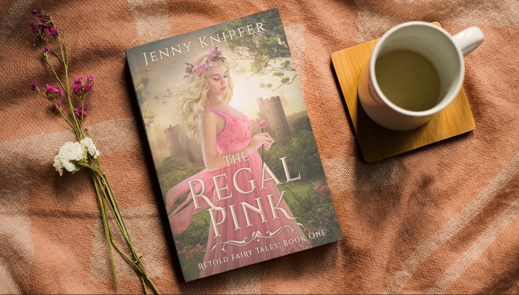 The Regal Pink by Jenny Knipfer with a simple cloth background. Flowers are to the book's left and a cup of coffee is to the book's right. 