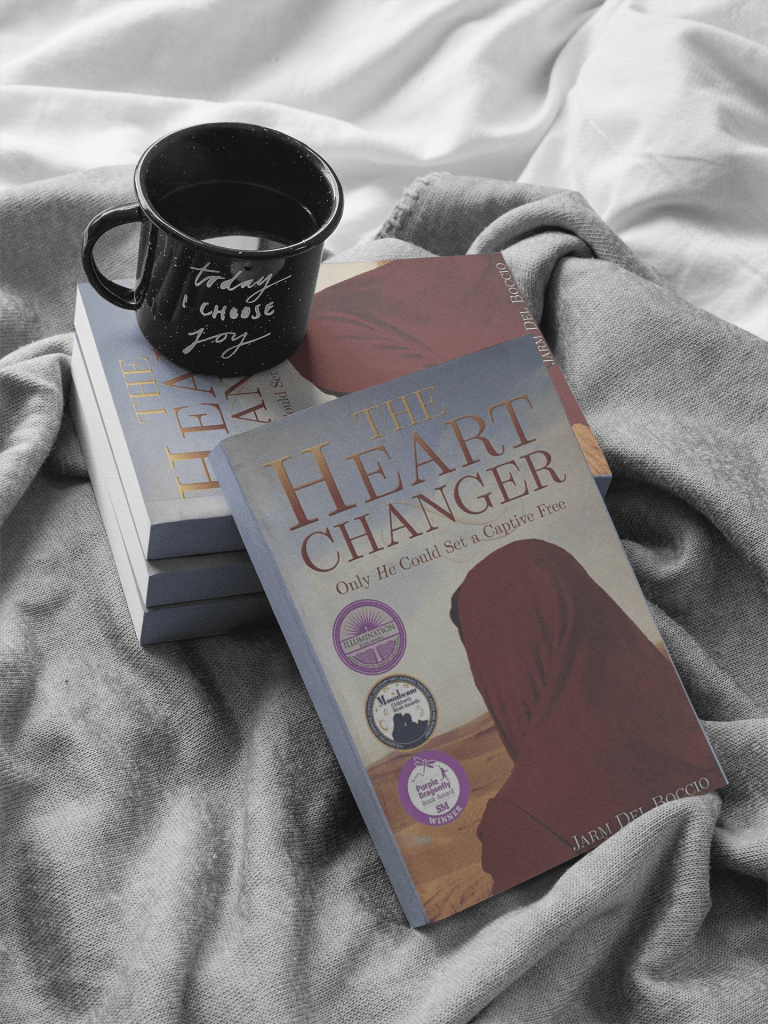 Stack of 3 books with The Heart Changer by Jarm Del Boccio leaned against them. On top of stack is a black mug that says "Today I Choose Joy."